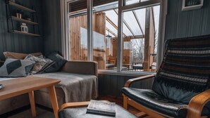 Een gezellige kamer met een houten bank, een leren fauteuil en een houten tafel.