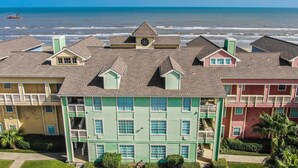 A beachfront hotel with multiple-story buildings, balconies, and a view of the ocean. - Poolside Retreat, Steps to the Ocean! (Galveston)