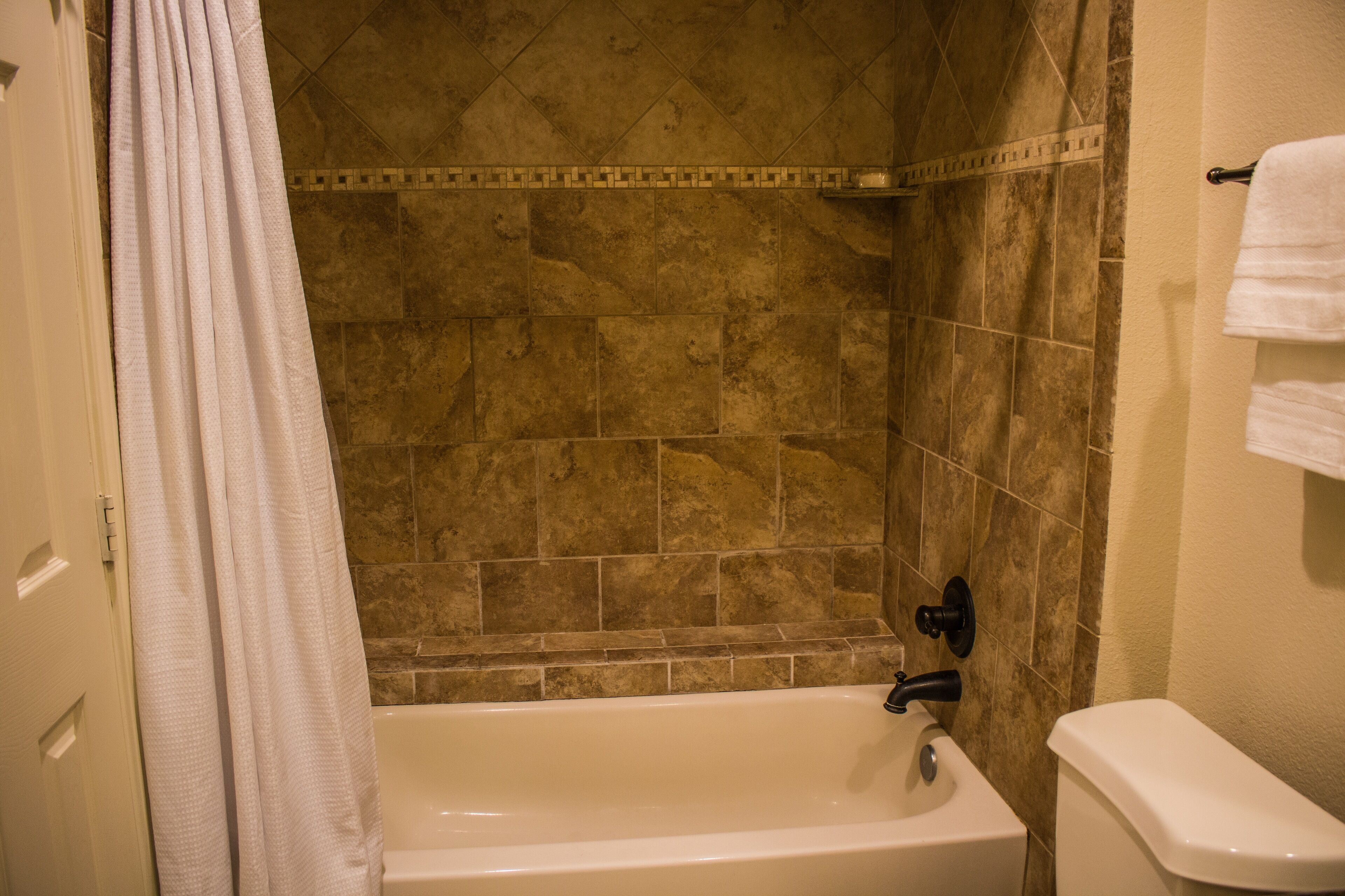 A bathroom with a bathtub, a toilet, and a shower curtain.