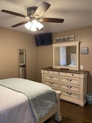 Une chambre à coucher comprenant un lit, une commode, un miroir, un ventilateur de plafond et une pancarte sur laquelle on peut lire : « Smith Lake Life ».
