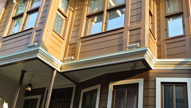 A brown two-story house with white trim, multiple windows, and a porch with a railing. - Emirhan Hotel - Adults Only (Istanbul)