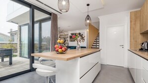 Een moderne keuken met een houten aanrechtblad, witte kasten en een glazen deur naar een balkon.