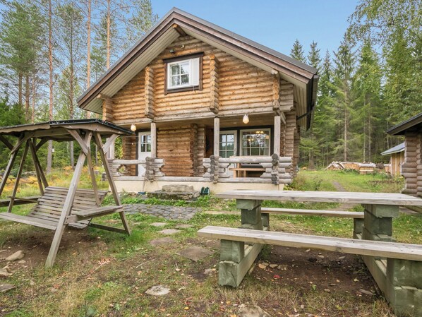Hirsihökkelissä on kuisti, keinut ja piknikpöytiä.