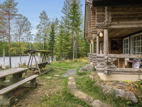 A cabin with a porch, a swing, and a stone pathway leading to a dock.