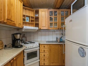 Eine Küche mit Holzausstattung, einem Herd, einem Kühlschrank und einer Dunstabzugshaube.