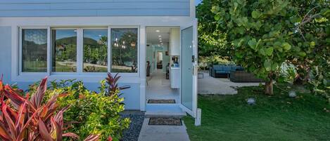 A modern two-story house with large windows, a visible kitchen, and a well-maintained garden.