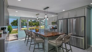 A modern kitchen with a large island, stainless steel appliances, and a view of the outdoors. - WOW! 3 BR! Remodeled waterfront unit, Sapphire Beach, ocean view, private patio (St Thomas)