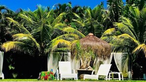 A swimming pool with a thatched-roof structure and white lounge chairs. - Pousada Terra Do Mar (Búzios)