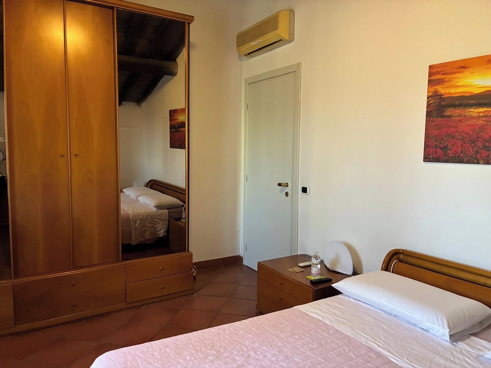 Ein Schlafzimmer mit einem Bett, einem Kleiderschrank, einem Nachttisch und einer Tür.