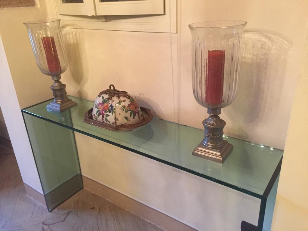 Une étagère en verre avec deux porte-bougies et un objet décoratif.