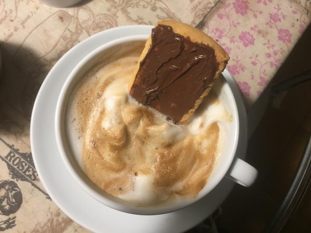A cup of coffee with a piece of chocolate on top.