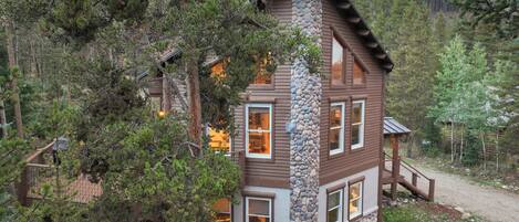 A cabin with a stone facade, wooden exterior, and multiple windows.