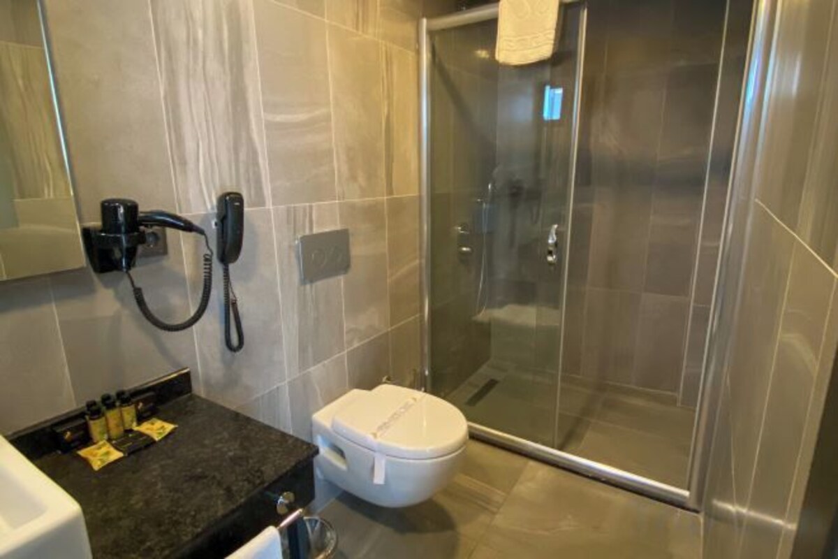 Un bagno moderno con box doccia in vetro, un water e un asciugacapelli su un supporto a parete.