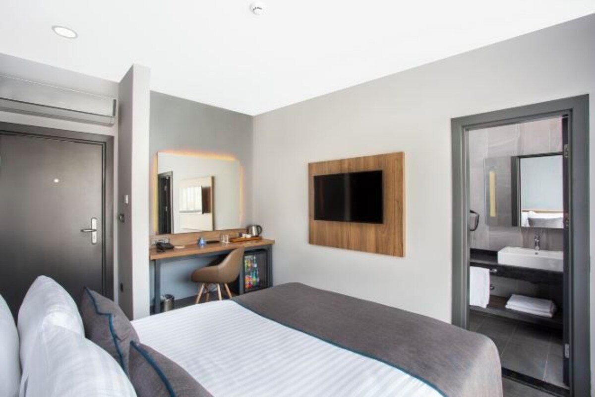 A hotel room with a bed, a desk, a TV, and a bathroom.