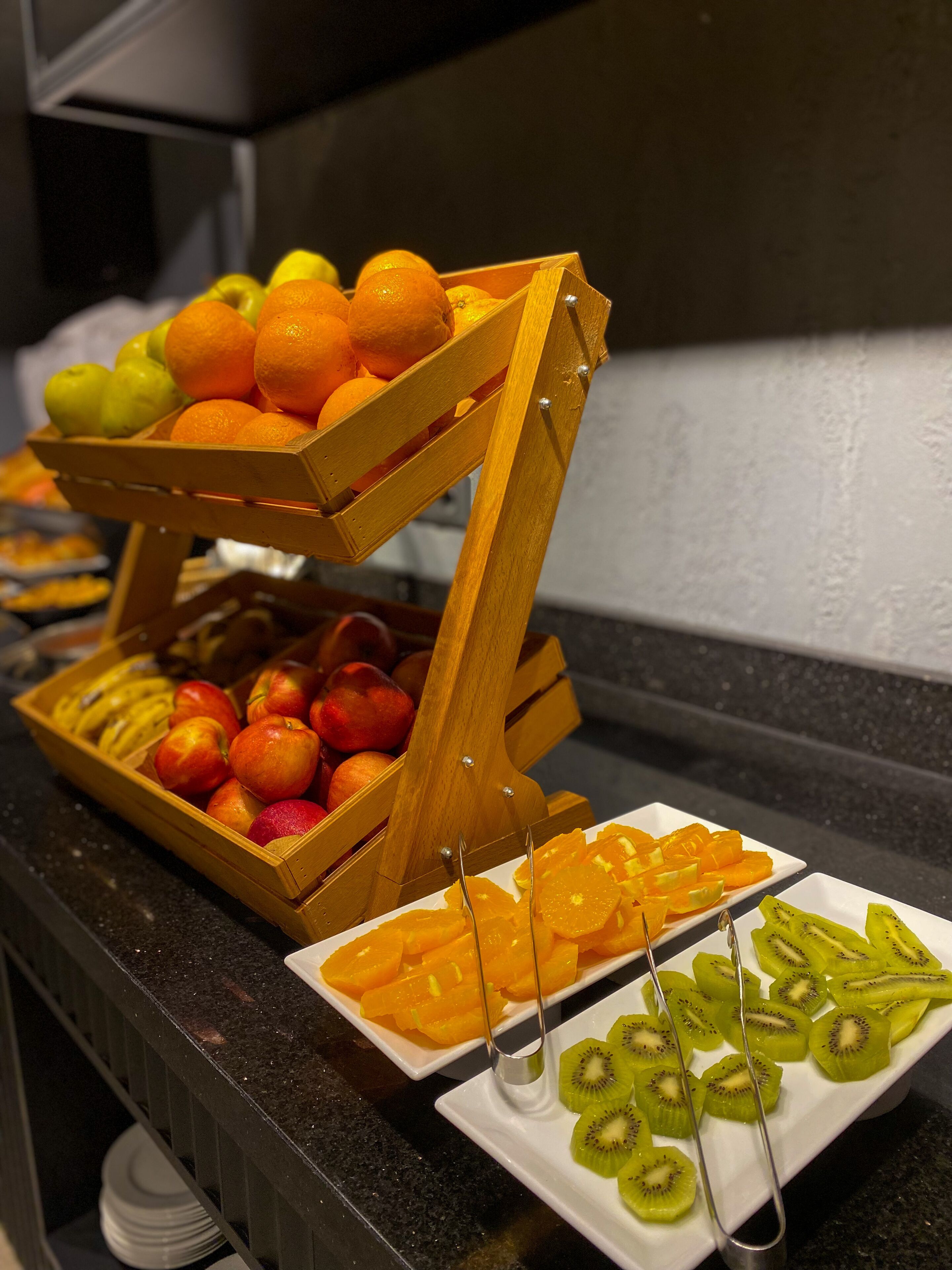 Une présentation de fruits comprenant des oranges, des pommes et des tranches de kiwi, disposés sur un comptoir.