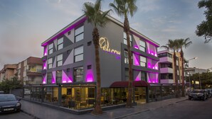 A modern building with a neon sign, large windows, and palm trees. - Falcon 1511 (Antalya)