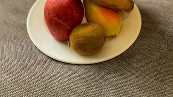 A plate with a banana, apple, peach, and kiwi on a textured surface.