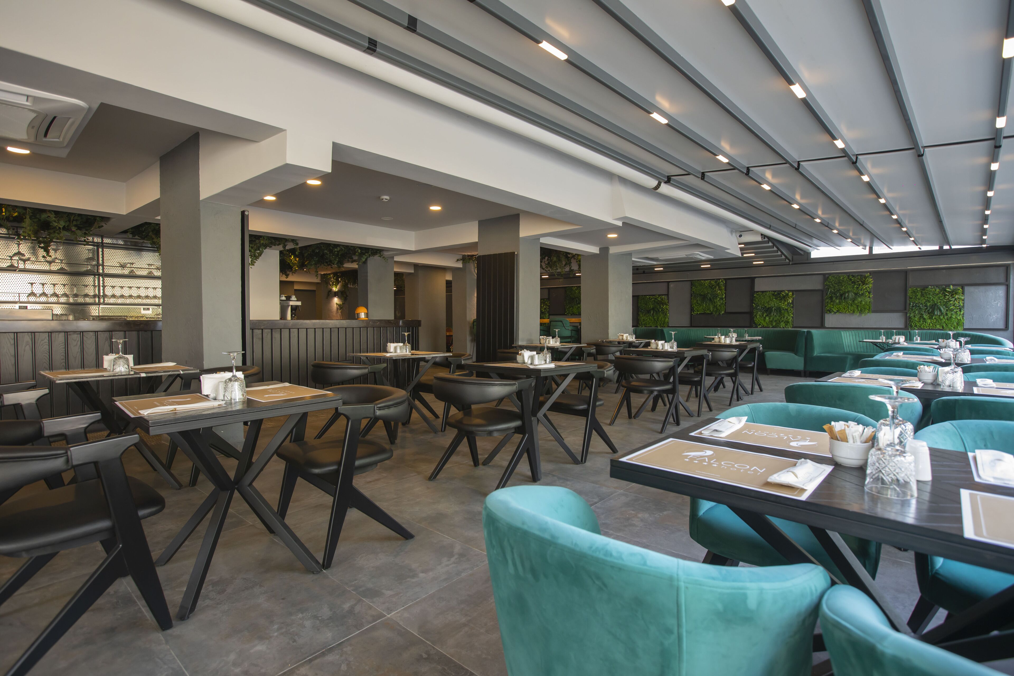 Un restaurante espacioso con techos altos, muebles modernos y vistas al exterior con zonas verdes.