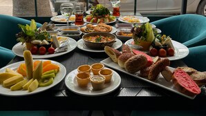 A table set with various dishes and drinks, viewed through a window with a view of parked cars and trees outside. - Falcon 1511 (Antalya)