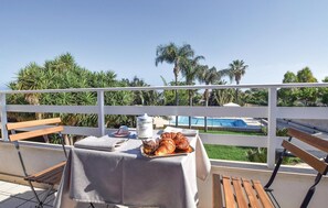 Ein Balkon mit Frühstückstisch, mit Blick auf einen Pool und Palmen.