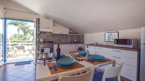 Une cuisine compacte avec des meubles blancs, un four à micro-ondes et un coin repas agrémenté d’assiettes et de chaises bleues.