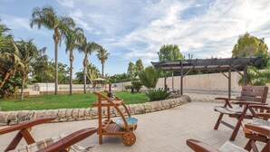 Un espace patio avec des chaises en bois et un chariot en bois, une piscine, des palmiers et une pergola.