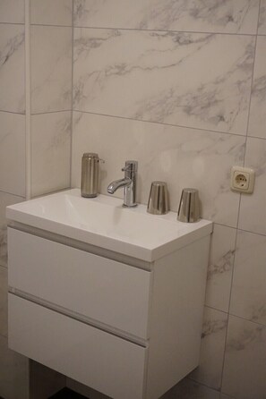 Une salle de bain avec un lavabo blanc, un seul robinet et un miroir.