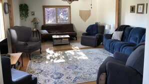 Ein Wohnzimmer mit einem braunen Sofa, einem blauen Sofa, einem Couchtisch und einem Deckenventilator.
