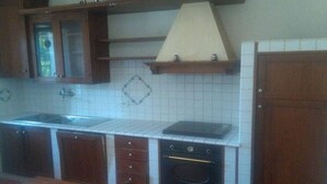 A kitchen with wooden cabinets, a stove, and a sink. - Holiday home in Val di Chiana (Castiglion Fiorentino)