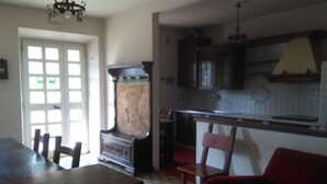 A kitchen with a wooden table, chairs, a red armchair, and a vintage refrigerator. - Holiday home in Val di Chiana (Castiglion Fiorentino)