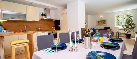 A modern dining area with a table set for four, featuring blue plates and candles.