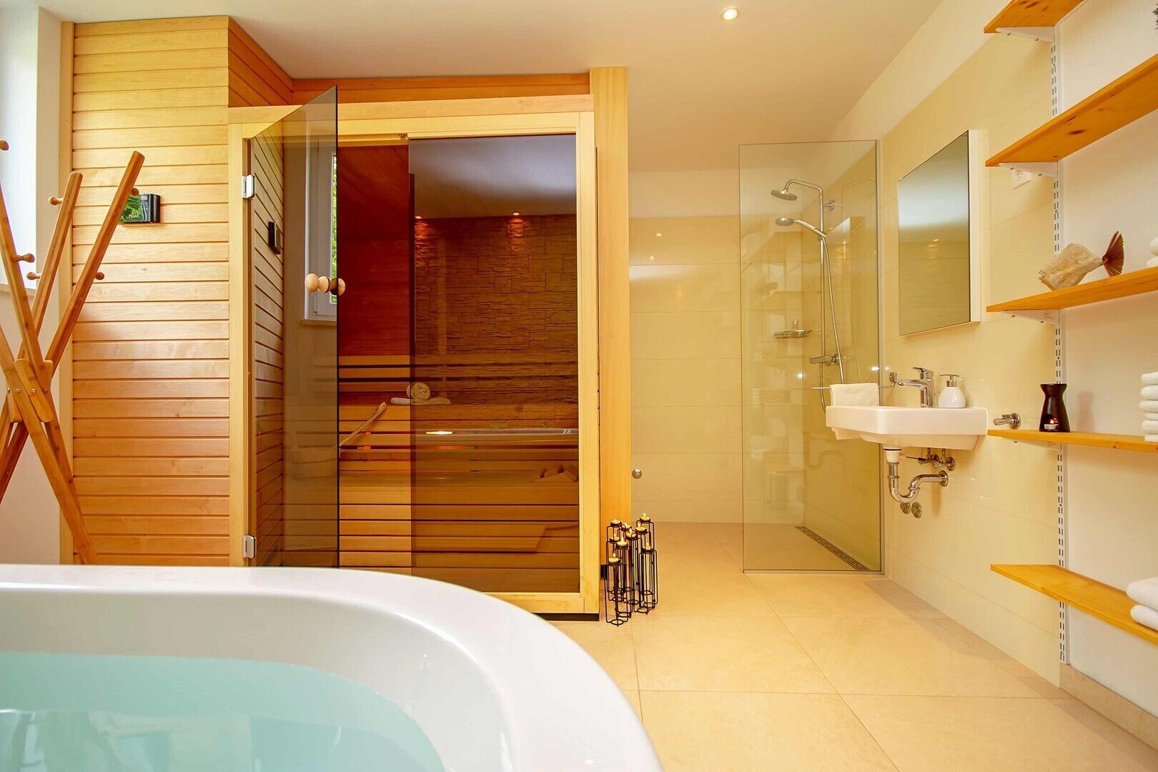 Une salle de bain moderne avec une douche à l’italienne en verre, une porte en bois et une baignoire blanche.