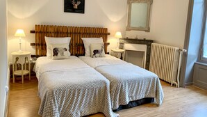 A double bed with a wooden headboard, two bedside tables with lamps, a fireplace, and a radiator.