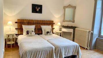 Un lit double avec une tête de lit en bois, deux tables de chevet avec des lampes, un radiateur et un miroir au mur.