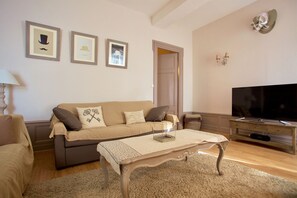 Una sala de estar con un sofá, una mesa de centro, un televisor y cuadros en la pared.