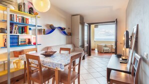 Un salón acogedor con comedor, una estantería y vistas al exterior.