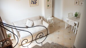 Een woonkamer met een bank, een eettafel met stoelen en een trap.