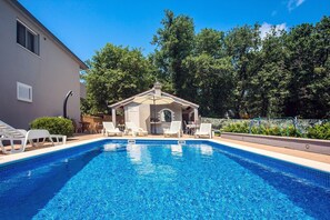 Ein Swimmingpool mit Liegestühlen und einem Pavillon.