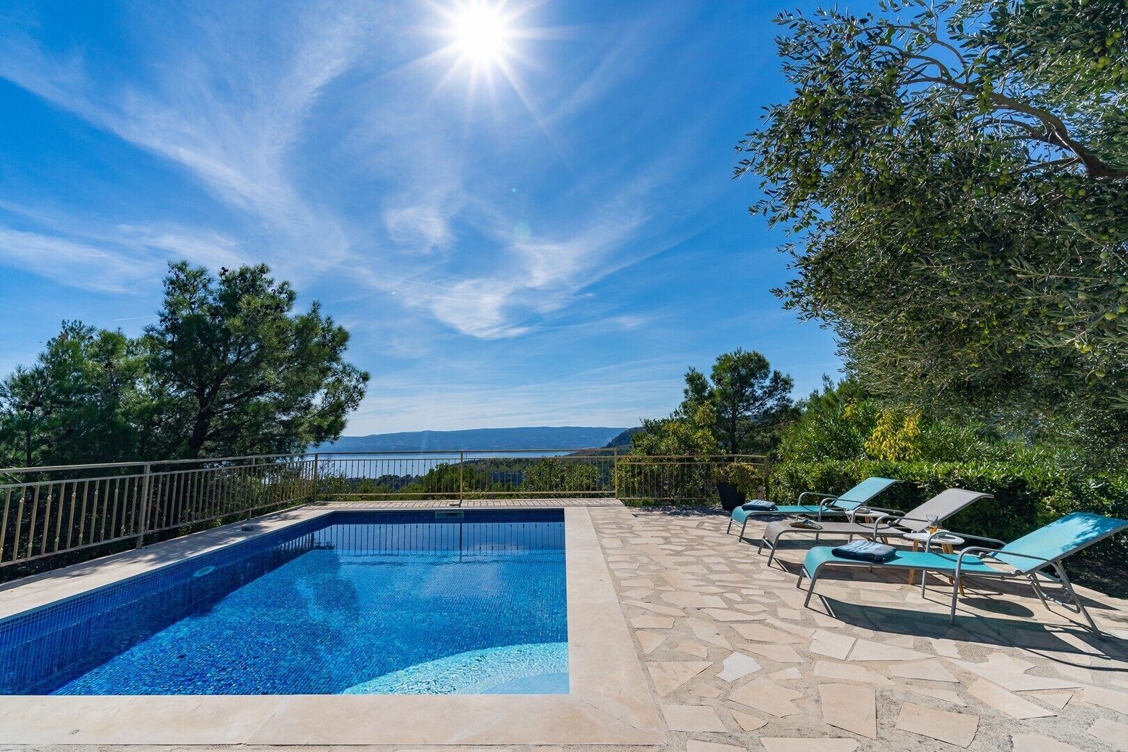 Una piscina con vistas despejadas del paisaje, rodeada de árboles y una terraza de piedra.