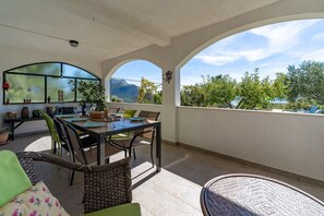 Eine Terrasse im Freien mit Esstisch, umgeben von Korbmöbeln.
