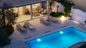 Uma área de piscina moderna ao ar livre, com espreguiçadeiras e um espaço para refeições.