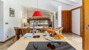 Une cuisine moderne avec un îlot central, un luminaire suspendu rouge et des aliments pour le petit-déjeuner disposés sur le comptoir.