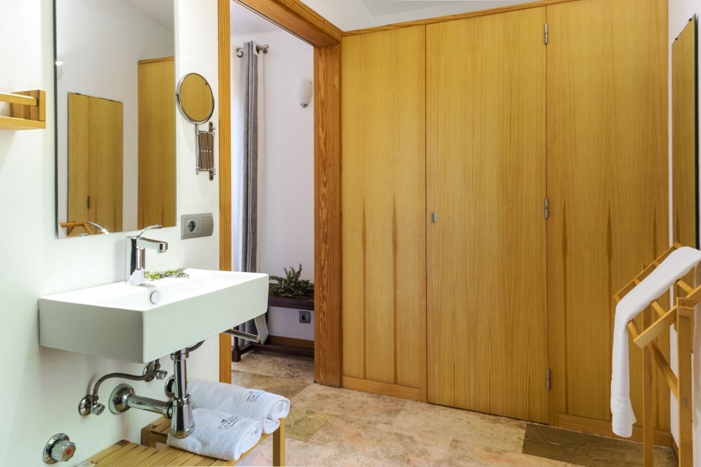 A bathroom with a sink, mirror, and wooden wardrobe.