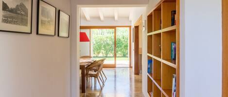A hallway with a dining area, wooden bookshelves, and framed pictures on the walls.