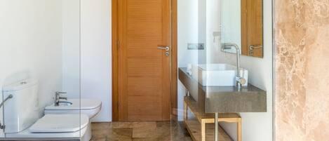 A modern bathroom with a toilet, sink, and mirror.