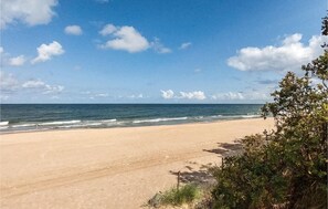 Uma praia com céu claro e ondas do oceano.