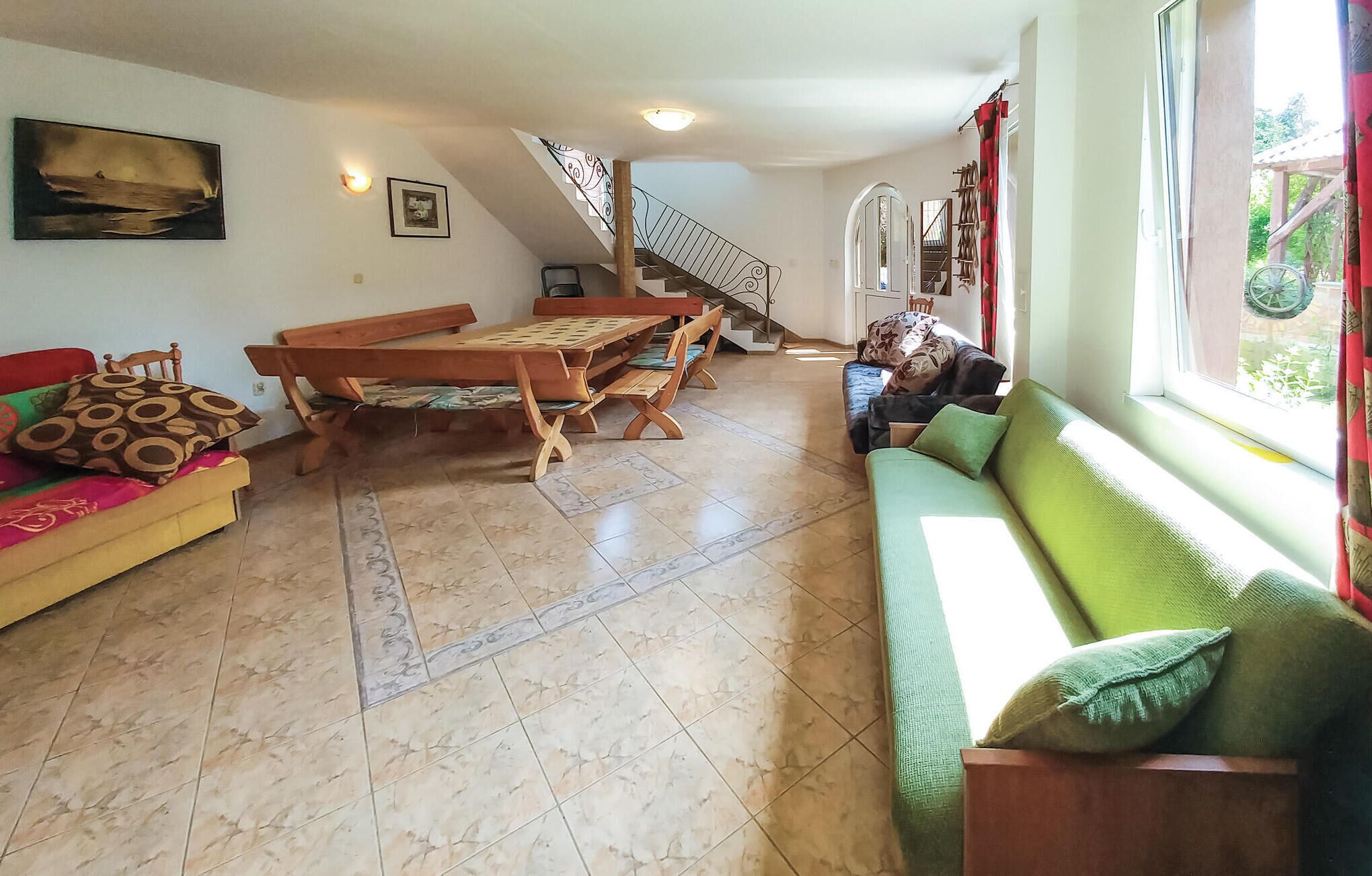 Un salon spacieux avec une table à manger en bois, un canapé et un escalier menant à l’étage supérieur.