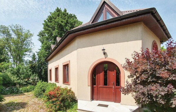 A building with a beige facade, a red door, and a triangular roof.