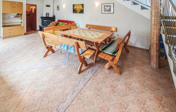 Uma área de refeições com uma mesa de madeira e bancos, uma lareira e uma escada.
