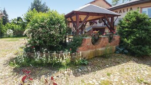 A rustic garden with a wooden pergola, a brick wall with a wheel, and a building labeled "DALIA".